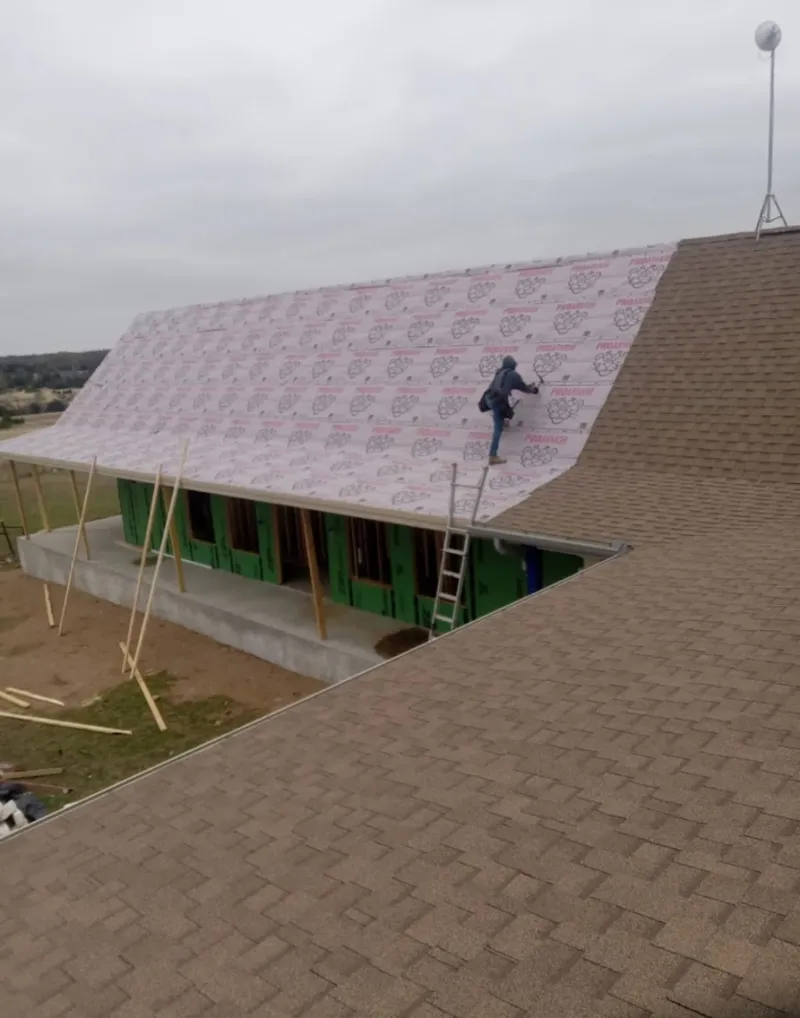 Worker preparing underlayment for a metal roof installation in Margate